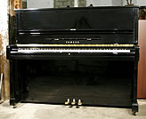 A Yamaha U1A upright piano with a black case and polyester finish. 