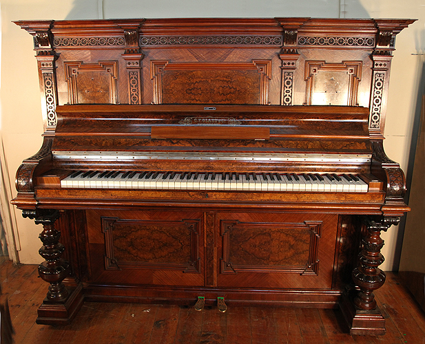 Glass upright piano with an ornate, walnut case and carved detail