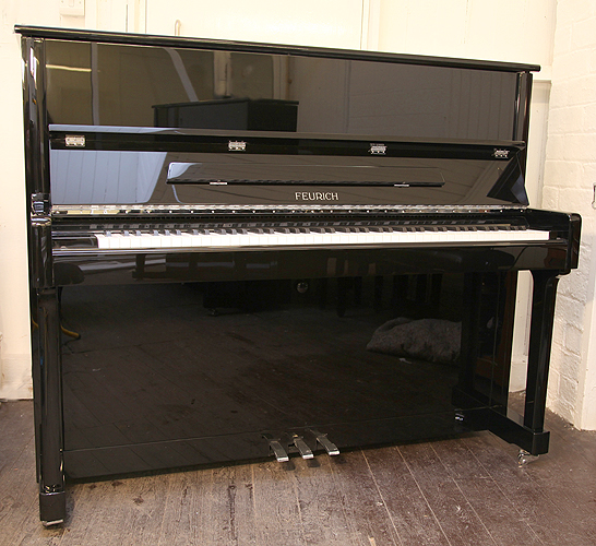A Brand New Feurich Model 122 upright piano with a black case and chrome fittings
