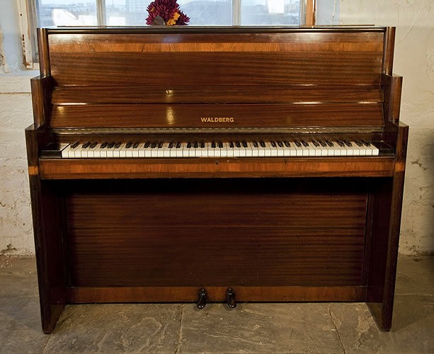 An Art-Deco Waldberg upright piano with a polished, mahogany case. 