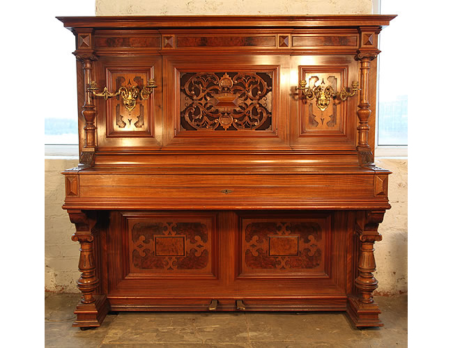 A 1900, Steingraeber upright piano with an ornately carved, walnut case. Piano features ornately carved pilasters, legs and panels