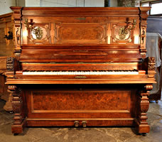 An Ehret upright piano with an ornately carved, rosewood and walnut case
