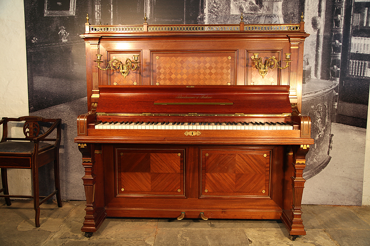 A 1926, Schiedmayer upright piano with an Empire style, mahogany case. Cabinet features marquetry inlaid panels and bronze decoration. 