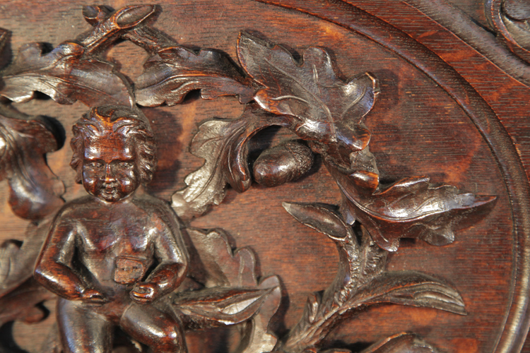 Mand piano ornately carved front panel featuring a central plaque with cherubs, oak leaves and acorns