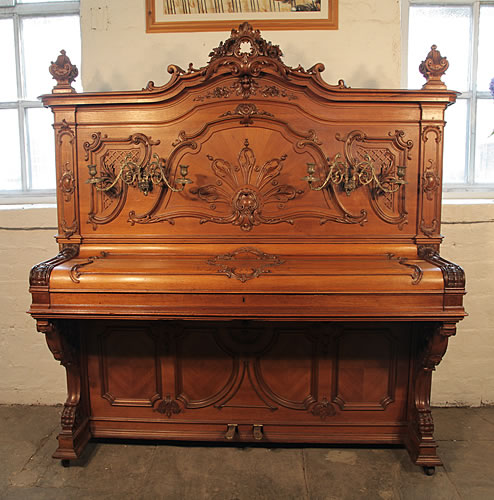 A Rococo style, Ludwig Adam upright piano with an ornately carved, walnut case and gilt detail.