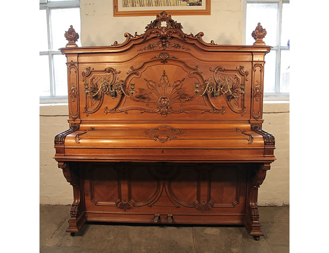 A Ludwig Adam upright piano with an ornately carved, rococo style, walnut case with gilt detail