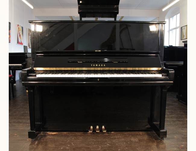 A  Yamaha u3 upright piano with a black case and brass fittings