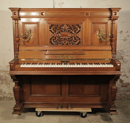 An 1897, Steingraeber upright piano with a walnut case, carved filgree panel and ornate brass candlesticks