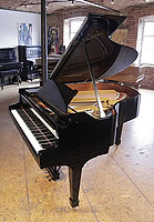 A 1922, Steinway Model M grand piano with a black case and spade legs. Piano has an eighty-eight note keyboard and a two-pedal lyre. 