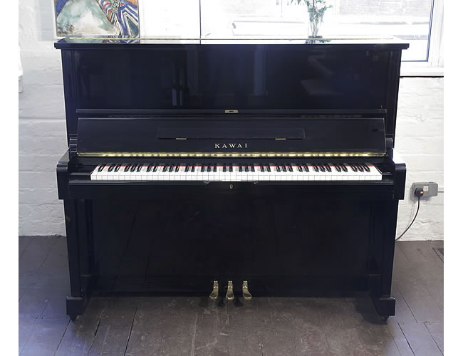 Reconditioned, 1991, Kawai SU-2L upright piano with a black case and brass fittings. Piano has an eighty-eight note keyboard and three pedals.   