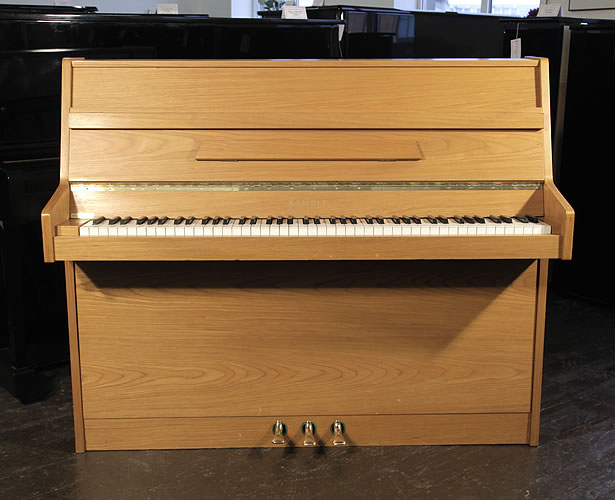A Kemble upright piano with a polished, walnut case
