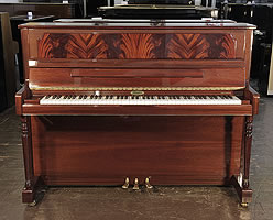 A Kemble upright piano with a mahogany case and flame mahogany panel.