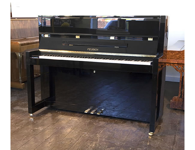 Brand new, Bauhaus style, Feurich Model 115 Premiere upright piano with a black case and polyester finish. Bauhaus style represented in the minimal, geometric style of the piano cabinet.  Piano  has an eighty-eight note keyboard and three pedals.