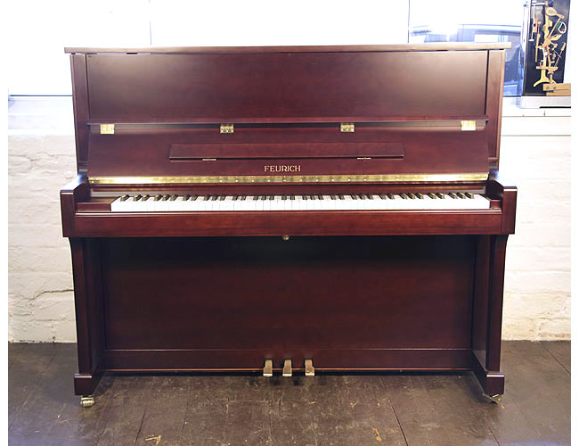 A brand new, Feurich Model 122 upright piano with a satin, mahogany case and brass fittings. Piano has an eighty-eight note keyboard and three pedals. .
