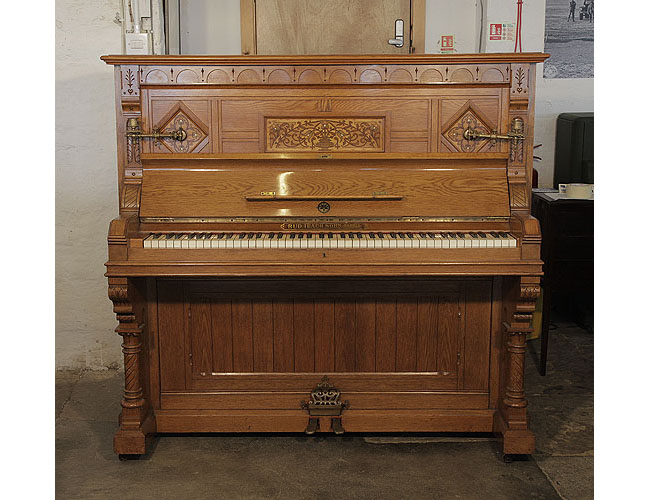 An 1895, English Gothic style, Ibach upright piano with a carved, oak case and ornate brass candlesticks and handles. Cabinet features traditional folk art motif carvings 