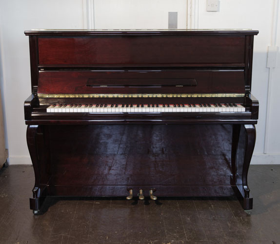Samick upright piano with a mahogany case and cabriole legs. Piano has an eighty-eight note keyboard and three pedals.