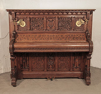  Renaissance style, Gebruder Knake upright piano for sale with an ornately carved, oak case. Cabinet features front panels carved with arabesque style, flowers, foliage and a central lyre. Seated dragons recline at the base of the Classical columnar, piano legs. Gothic tracery and arches feature strongly throughout the cabinet architecture. 