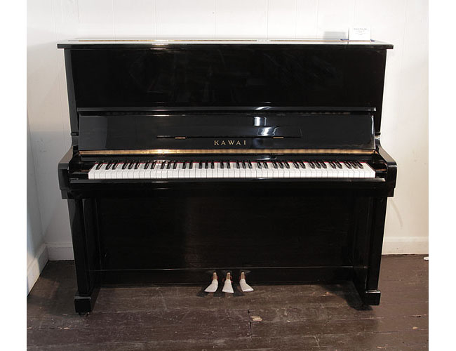 Pre-owned, Kawai KU-1B upright piano with a black case and polyester finish. Piano has an eighty-eight note keyboard and three pedals.   