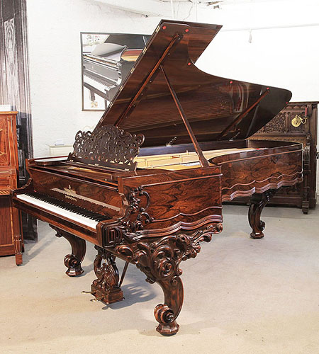 An 1874, Steinway Centennial  concert grand piano with a rosewood case, filigree music desk and ornately carved, reverse scroll legs. Cabinet features piano cheeks carved with scrolling foliage. Piano has an eighty-eight note keyboard and a two-pedal lyre.