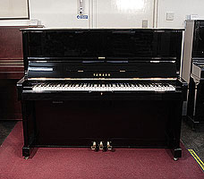 A 1977, Yamaha U1 upright piano with a black case and polyester finish. Piano has an eighty-eight note keyboard and three pedals. 