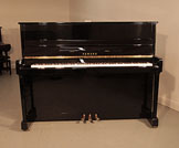 Piano for sale.  Yamaha P116 upright piano for sale with a black case and brass fittings. Piano has an eighty-eight note keyboard and three pedals. 