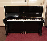 Piano for sale. A 1975, Yamaha U1 upright piano with a black case and polyester finish. Piano has an eighty-eight note keyboard and three pedals. 