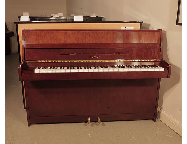 A 1985, Kawai CX-4S upright piano for sale with a walnut case and brass fittings. Piano has an eighty-eight note keyboard and two pedals.  