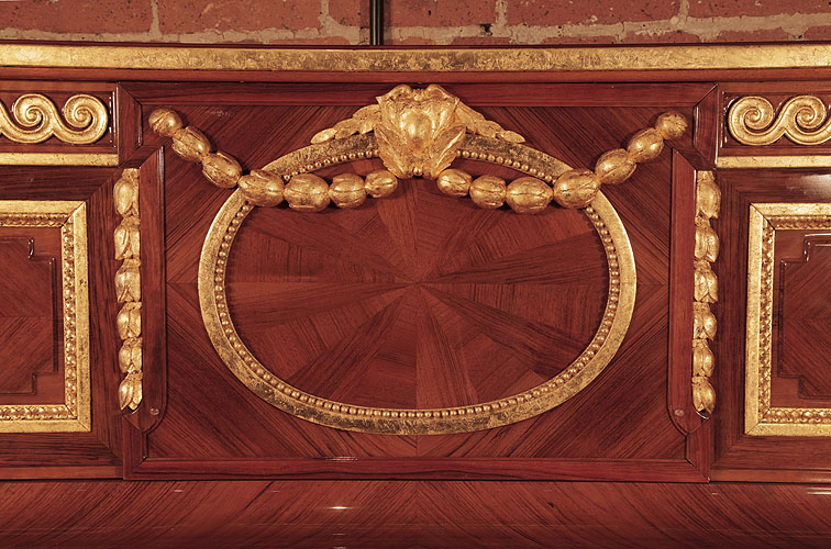 Steinway front panel inlaid with walnut in a sunburst design. Panel features a gold oval with a beading surround, draped with swagged flowers and a central cartouche