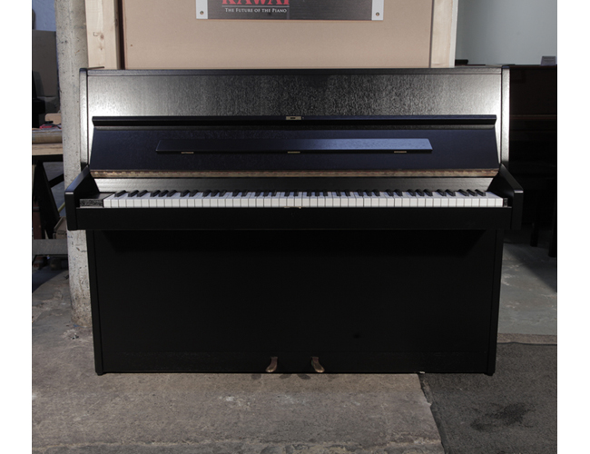Pre-owned, 1972, Carl Sauter 108 upright piano with a black, polished case and brass fittings. Piano has an eighty-eight note keyboard and two pedals.