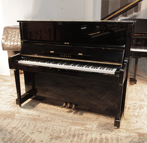  Reconditioned,  1977, Yamaha U1 upright piano in black gloss with brass fittings. Piano has an eighty-eight note keyboard and three pedals. 