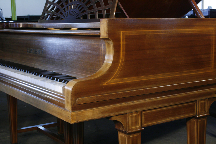 Bechstein rounded piano cheek with satinwood stringing accents and a linear case moulding that wraps around the base of the cabinet