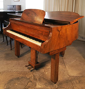 An Art Deco style Strohmenger baby grand piano with a walnut case. Piano Legs amd lyre feature strong geometric styling