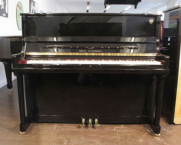 A Brand New Steinberg Model AT-K23 upright piano with a black case and brass fittings. Piano features a slow fall mechanism, eighty-eight note keyboard and three pedals.