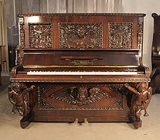 A Leitter & Winkelmann upright piano with an ornately, carved rosewood case. Cabinet appears to blend disparate design styles of the Medieval and Rococo. Front panels and pilasters are naively carved with creation myth scenes of Adam and Eve. The lower half of the piano exhibits more of a Rococo influence. The piano legs are elegantly carved, cherub caryatids. 