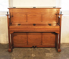 A 1903, Arts and Crafts style, Bluthner upright piano with a polished, oak case, sculptural candlesticks and ornate, iron hinges