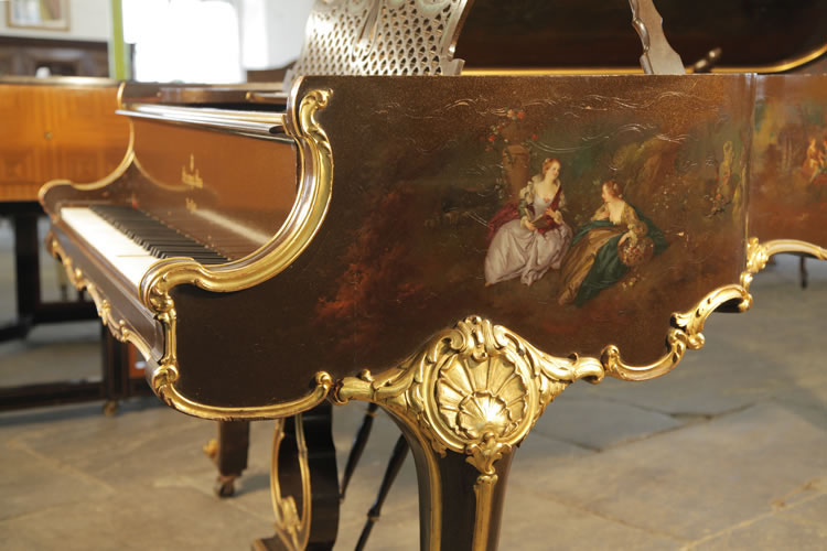 Steinway Model B ornately carved, piano cheek with gilt accents. The hand-painted scene features two ladies sitting outdoors discussing a book and gathering flowers in a basket. 