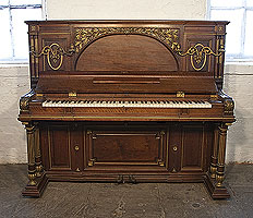 An 1892, Erard upright piano with a Renaissance style walnut case with gilt accents. Cabinet features ancient Roman elements including doric columns, rosettes and a front panel carved with myrtle