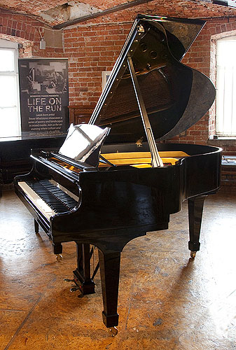 A 1951, Steinway Model S baby grand piano with a black case and spade legs. Piano has an eighty-eight note keyboard and a two-pedal lyre.