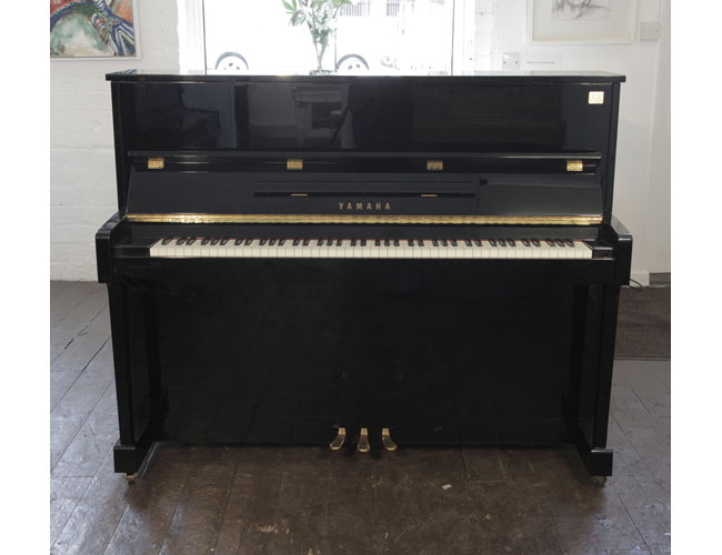 Reconditioned, 2000, Yamaha ET121 upright piano for sale with a black case and brass fittings. Piano has an eighty-eight note keyboard and three pedals. 