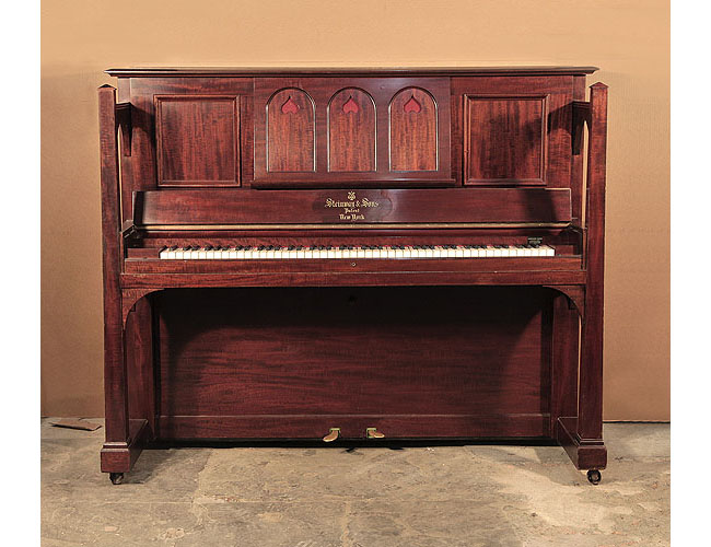 Arts and Crafts style, 1905, Steinway Vertegrand upright piano for sale with a figured, mahogany case and large sculptural legs. Cabinet features a wide music desk in a three arch design with cut-out inverted hearts backed with red felt.