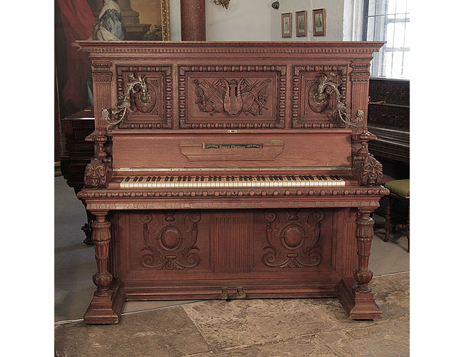 Georg Fortner upright piano for sale with a carved, mahogany case in high relief. The candlesticks are in an organic foliar design. The piano cheek featres a carved grotesque head. The cabinet carvings were created by the famous wood sculpter, Julius Bechler, wood artist for King Ludwig II 