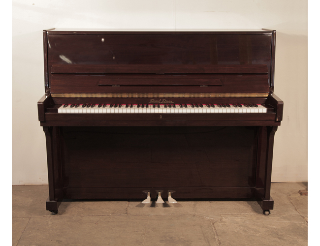 A 2001, Pearl River upright piano with a mahogany case and polyester finish. Piano has an eighty-eight note keyboard and and three pedals.