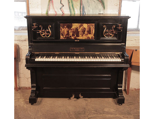 A 1905, Brinsmead upright piano with a polished, black case and central panel featuring a crystoleum image of a Classical scene.