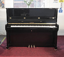 A brand new, Feurich Model 122 upright piano with a black case and brass fittings