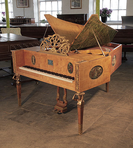 A 1918, Soren Jensen model D butterfly grand piano with a polished, maple case. The gilt music desk is in an openwork, scrolling design featuring flowers, shells amd swags. Piano sits on three square, tapered legs with bronze female nude, caryatids adorning the top. Cabinet features hand-painted ovals by Danish artist Gudmund Hentze. 