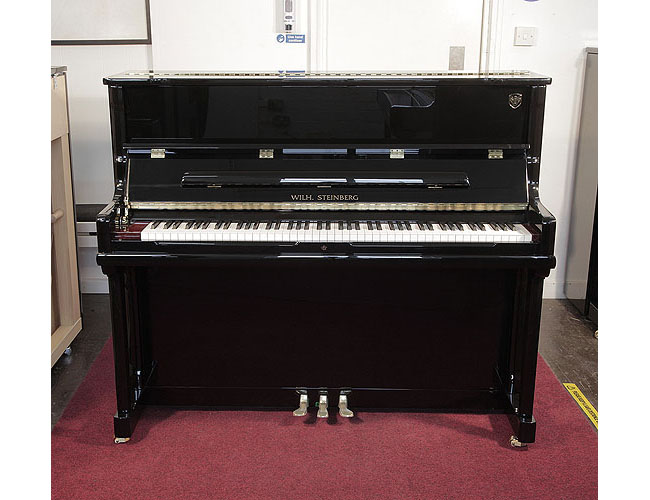 Brand new, Wilh. Steinberg Model AT-K23 upright piano with a black case and brass fittings. Piano lid features a slow fall mechanism. Piano has an eighty-eight note keyboard and three pedals. 