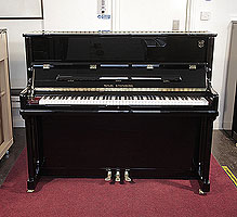 A brand new, Wilh. Steinberg Model AT-K23 upright piano with a black case and brass fittings.