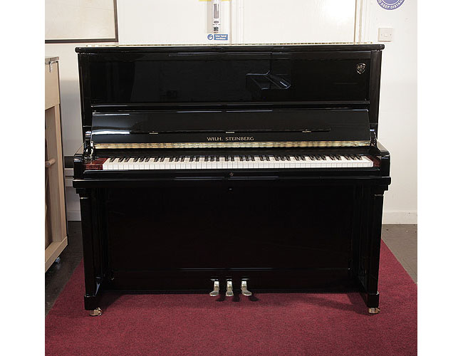 Brand new, Wilh. Steinberg Model AT-K30 upright piano with a black case and brass fittings. Piano features a walnut key block and slow fall mechanism. Piano has an eighty-eight note keyboard and three pedals. 
