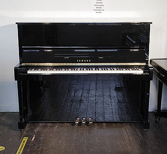 A reconditioned, 1993, Yamaha MC10A upright piano with a black case and polyester finish. Piano has an eighty-eight note keyboard and three pedals