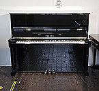 Piano for sale. A reconditioned, 1993, Yamaha MC10A upright piano with a black case and polyester finish. Piano has an eighty-eight note keyboard and three pedals.